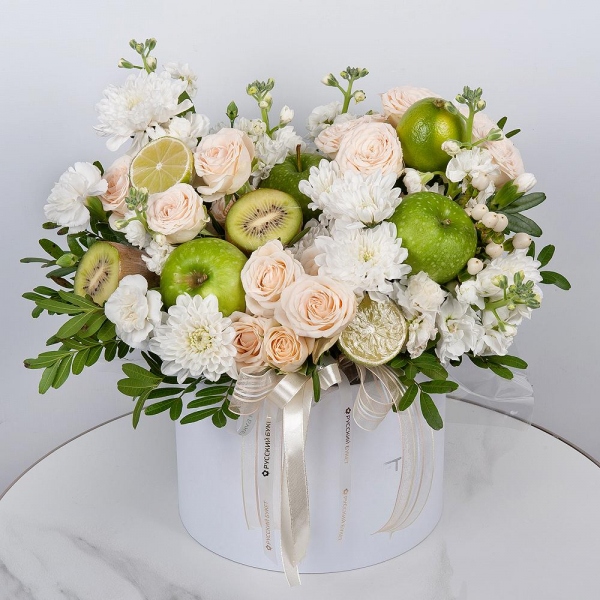 Baltica White Spray Chrysanthemum - 3, Peony sprayrose - 3, White Matthiola - 2, White spray carnation - 3, Round flower box medium, Oasis, Pistachio, Hypericum, Apple, 1 pc., Kiwi, Lemon, 1 pc., Wrapping Paper